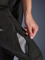 Alpinestars Stella Andes V4 Drystar® Damen-Hose, Motorradhose, Schwarz, Nahaufnahme einer Hand beim Öffnen der Oberschenkelbelüftung mit Reißverschluss, um das Mesh-Futter für die Luftzirkulation freizulegen, strapazierfähige Adventure-Textilausrüstung