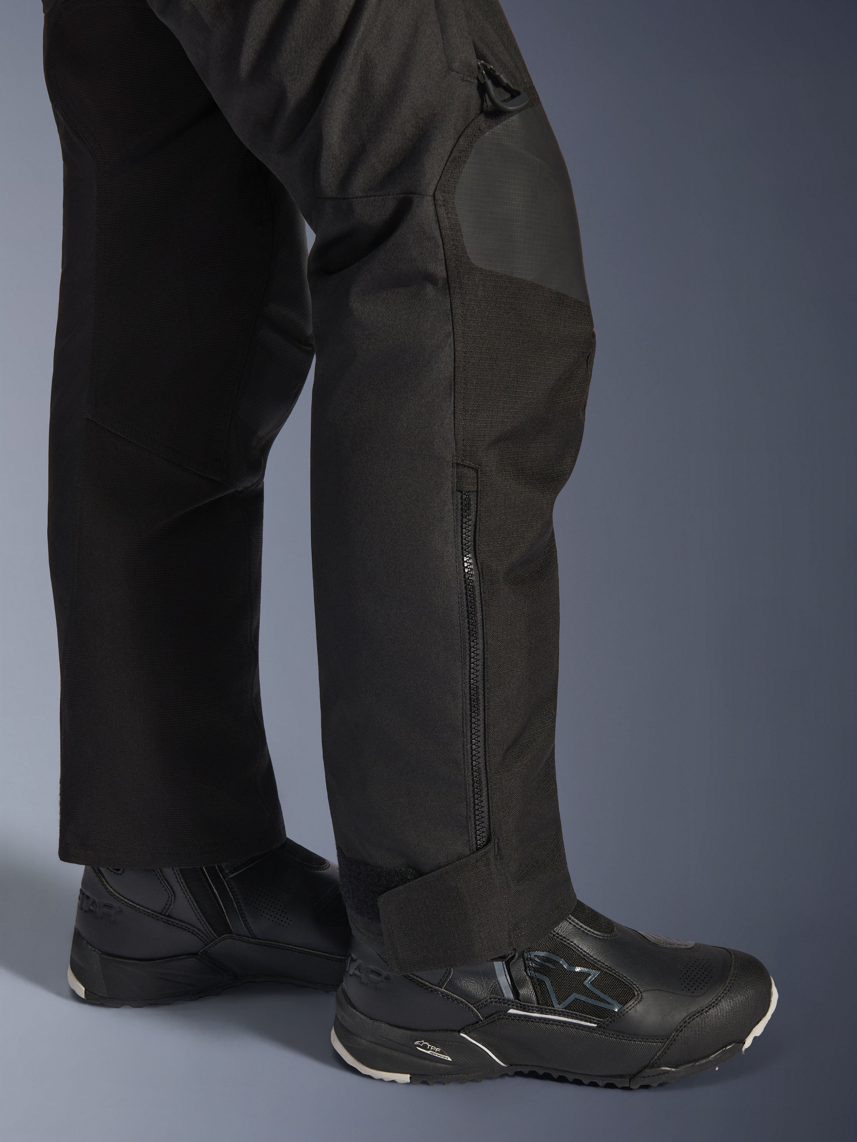 Alpinestars Stella Andes V4 Drystar® Hose, Motorradhose für Damen, Schwarz, Nahaufnahme des Unterschenkels mit seitlichem Reißverschluss und verstellbarem Knöchelbund, getragen mit schwarzen Alpinestars Motorradstiefeln
