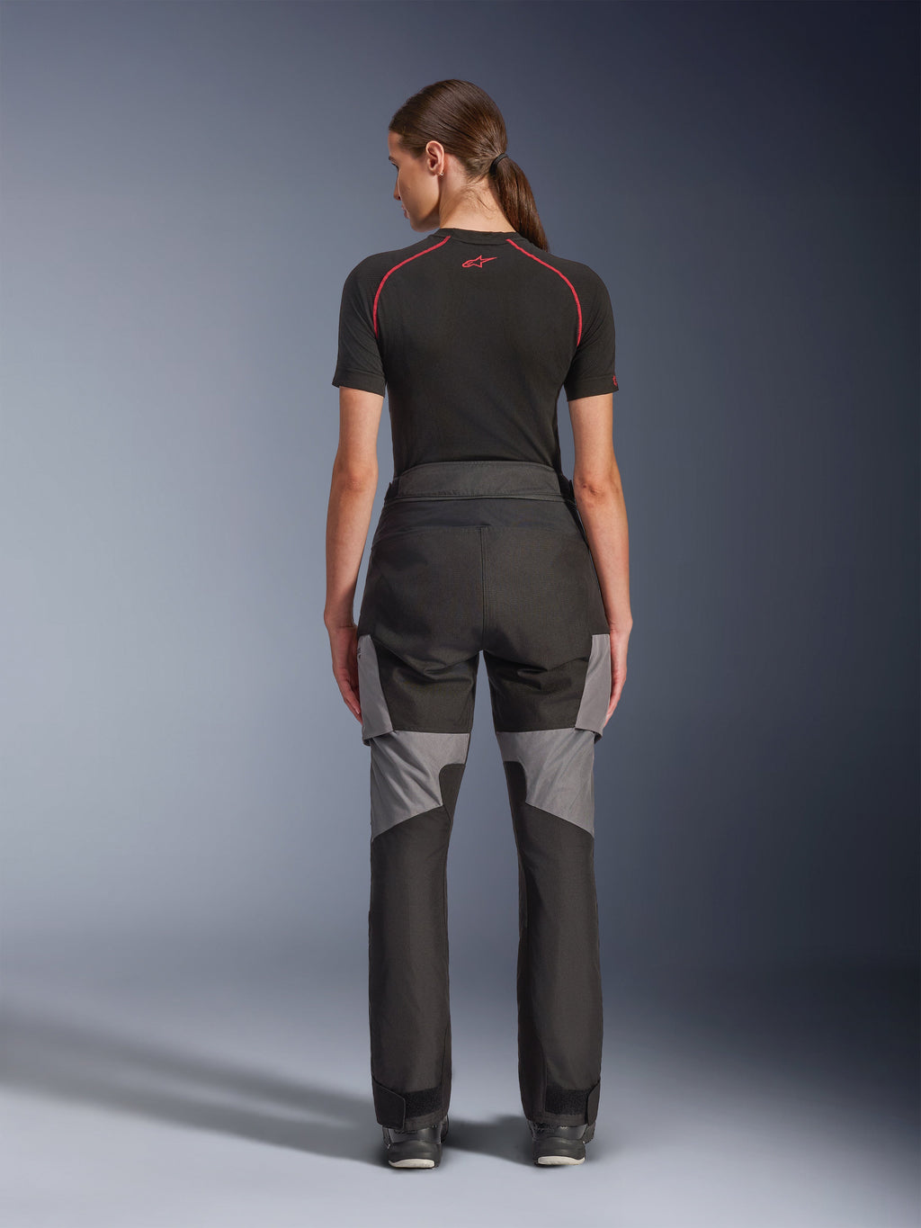 Alpinestars Stella Andes V4 Drystar® Hose, Motorradhose für Damen, Schwarz und Dunkelgrau, Rückansicht mit grauen Ripstop-Verstärkungen und ergonomischem Design, getragen mit einem schwarzen technischen Base Layer, Adventure-Touring-Fahrerausrüstung
