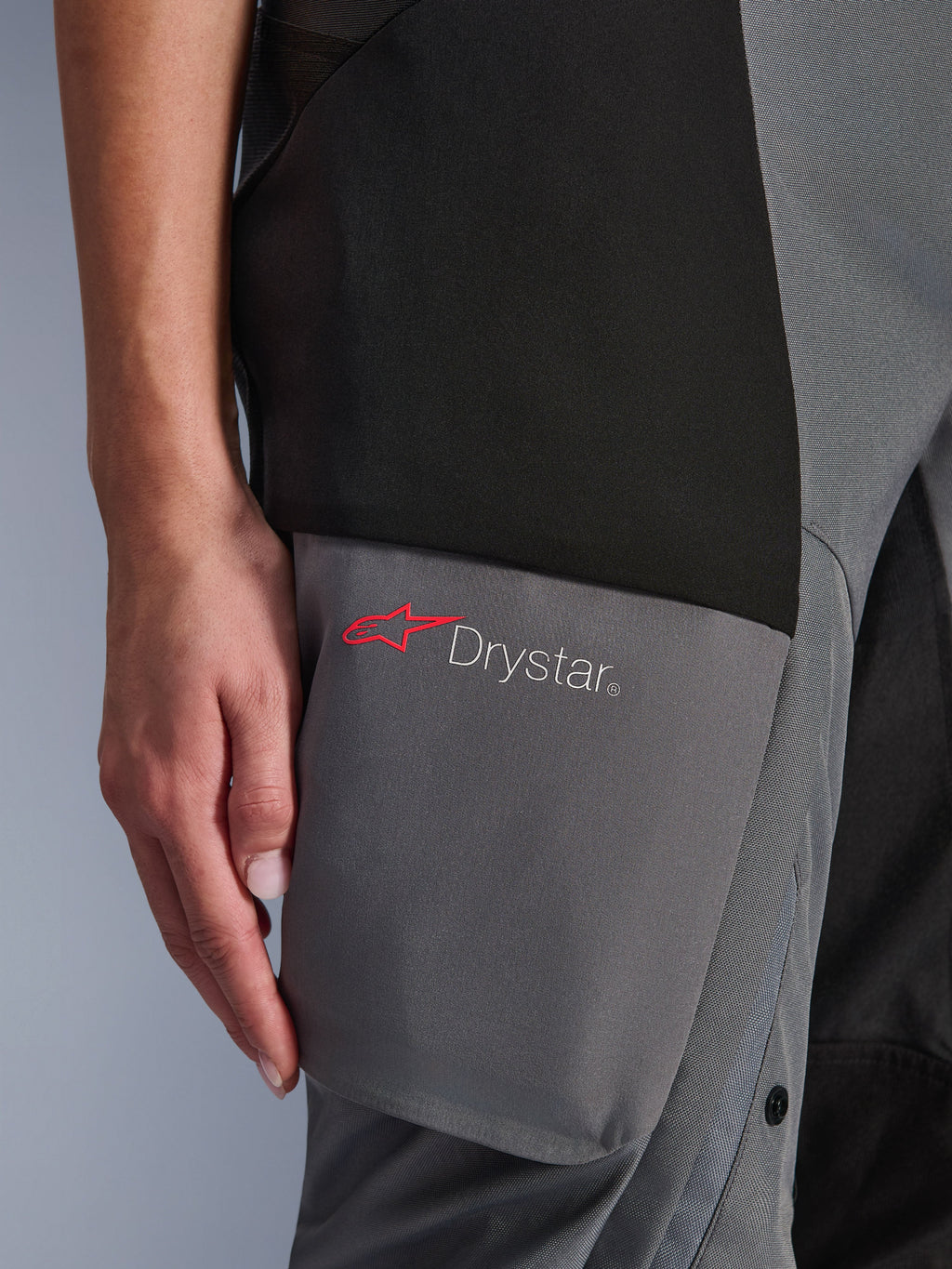 Alpinestars Stella Andes V4 Drystar® Hose, Adventure-Tourenhose für Damen, Schwarz und Dunkelgrau, Detailansicht des Oberschenkelbereichs mit Drystar-Logo und rotem Alpinestars-Stern auf verstärkten Textilpaneelen
