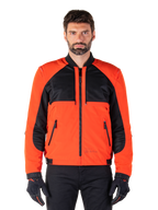 Alpinestars Mootant Wasserdichter Parka in Spicy Orange und Schwarz, modulare Motorradjacke in Bomberjacken-Konfiguration an einem männlichen Modell, mit schwarzen Mesh-Einsätzen im oberen Brustbereich, leuchtend orangefarbenem Torso und Ärmeln, Frontreißverschluss und Rippkragen, kombiniert mit schwarzen Handschuhen und einer schwarzen Hose.