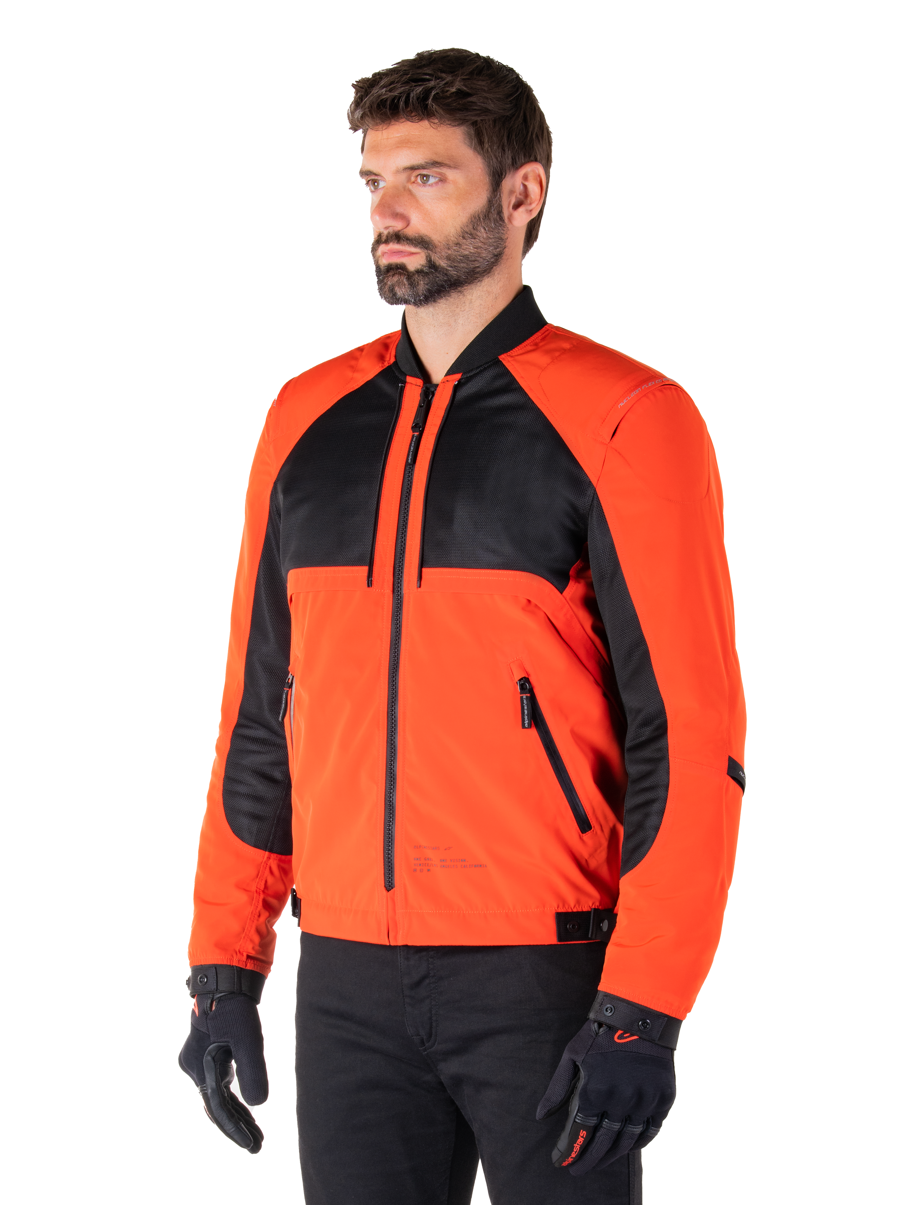 Alpinestars Mootant wasserdichter Parka in Spicy Orange und Schwarz, modulare Motorradjacke in der Bomberjacken-Konfiguration, mit schwarzen Mesh- und orangefarbenen Textileinsätzen, moderne urbane Fahrausrüstung, getragen mit schwarzen Handschuhen
