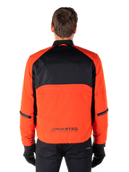Alpinestars Mootant Wasserdichter Parka, Motorradjacke, Spicy Orange und Schwarz, Rückansicht, mit schwarzem Mesh am oberen Rücken und orangefarbenem unterem Panel mit MO.ST.EQ. Logo, kombiniert mit schwarzer Hose und Handschuhen