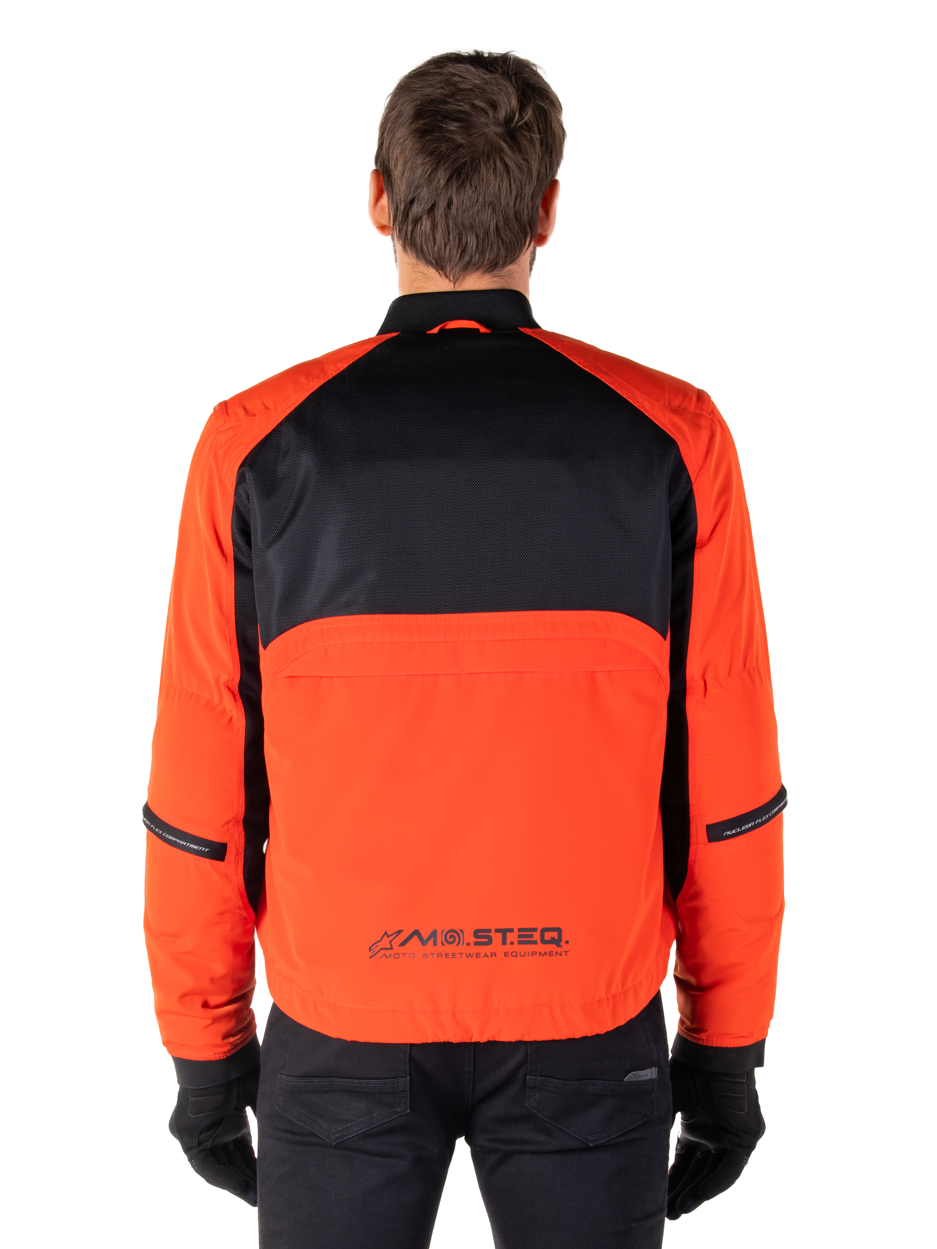 Alpinestars Mootant Wasserdichter Parka, Motorradjacke, Spicy Orange und Schwarz, Rückansicht, mit schwarzem Mesh am oberen Rücken und orangefarbenem unterem Panel mit MO.ST.EQ. Logo, kombiniert mit schwarzer Hose und Handschuhen