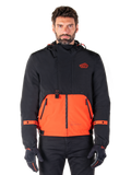 Alpinestars Mootant Waterproof Parka, modulare Motorradjacke in Spicy Orange und Schwarz, von einem Model mit passenden Handschuhen getragen, Kapuzendesign mit zweifarbigen Einsätzen, Frontreißverschluss und verstellbare Bündchen, moderne urbane Motorradbekleidung