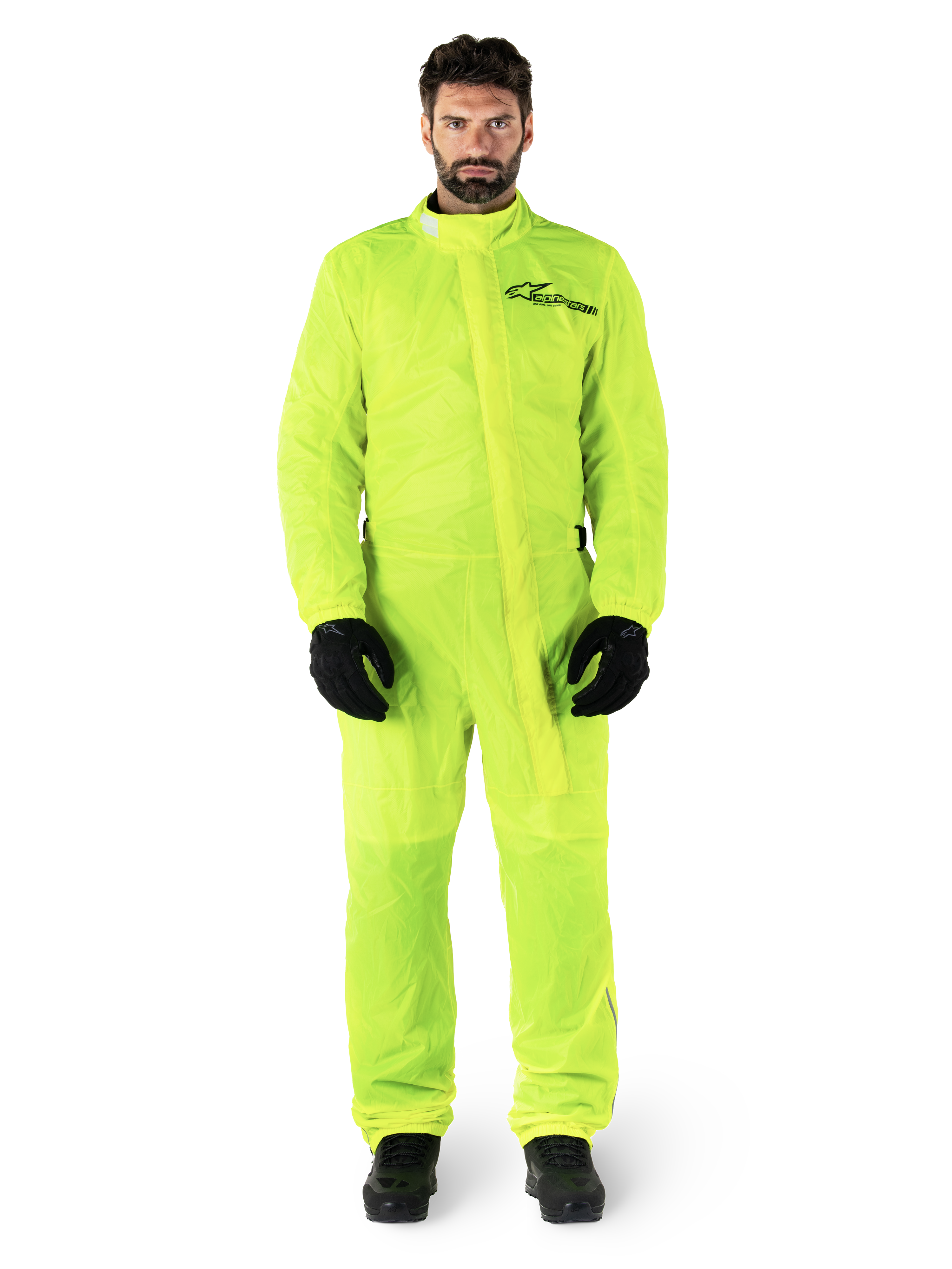 Alpinestars Hurricane Rain V2 Anzug, Motorrad-Regenanzug, Gelb Fluo, männliches Model in Ganzkörperschutz mit schwarzen Handschuhen und Stiefeln, hochgeschlossener Kragen mit vorderer Windschutzleiste, reflektierendes Logo auf der Brust, gut sichtbare wasserdichte Ausrüstung
