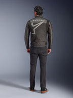 Alpinestars Axton Jacke, Motorradjacke, Schwarz Anthrazit Rot Tangerine, Rückansicht mit großem grauem Alpinestars-Logo und Sterngrafik, Akkordeon-Schulterpaneele, getragen mit schwarzer Hose und schwarzen Freizeitschuhen.