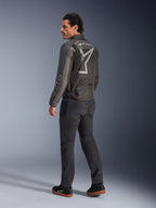 Alpinestars Axton Jacke, Motorradjacke für Herren, Schwarz und Anthrazit, Rückansicht mit einem großen grauen, umlaufenden Logo und Akkordeon-Stretcheinsätzen an den Schultern, getragen mit dunkler Fahrhose und schwarzen Sneakern, urbaner, zeitgemäßer Stil mit Racing-Tradition.