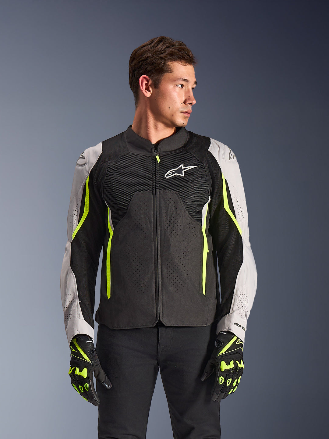 Alpinestars AST V3 Air Jacke, Motorradjacke, Schwarz und Grau mit Neongelben Streifen, Perforiertes Material für Atmungsaktivität, Passende Handschuhe, Person trägt Jacke
