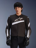 Alpinestars T-GP Plus R V4 Jacke, Textil-Motorradjacke, Schwarz und Weiß, mit weißen diagonalen Akzenten und Markenlogos auf Brust und Ärmeln, getragen von einem Modell mit schwarzen Motorradhandschuhen, sportliche Passform für Straßenfahrten