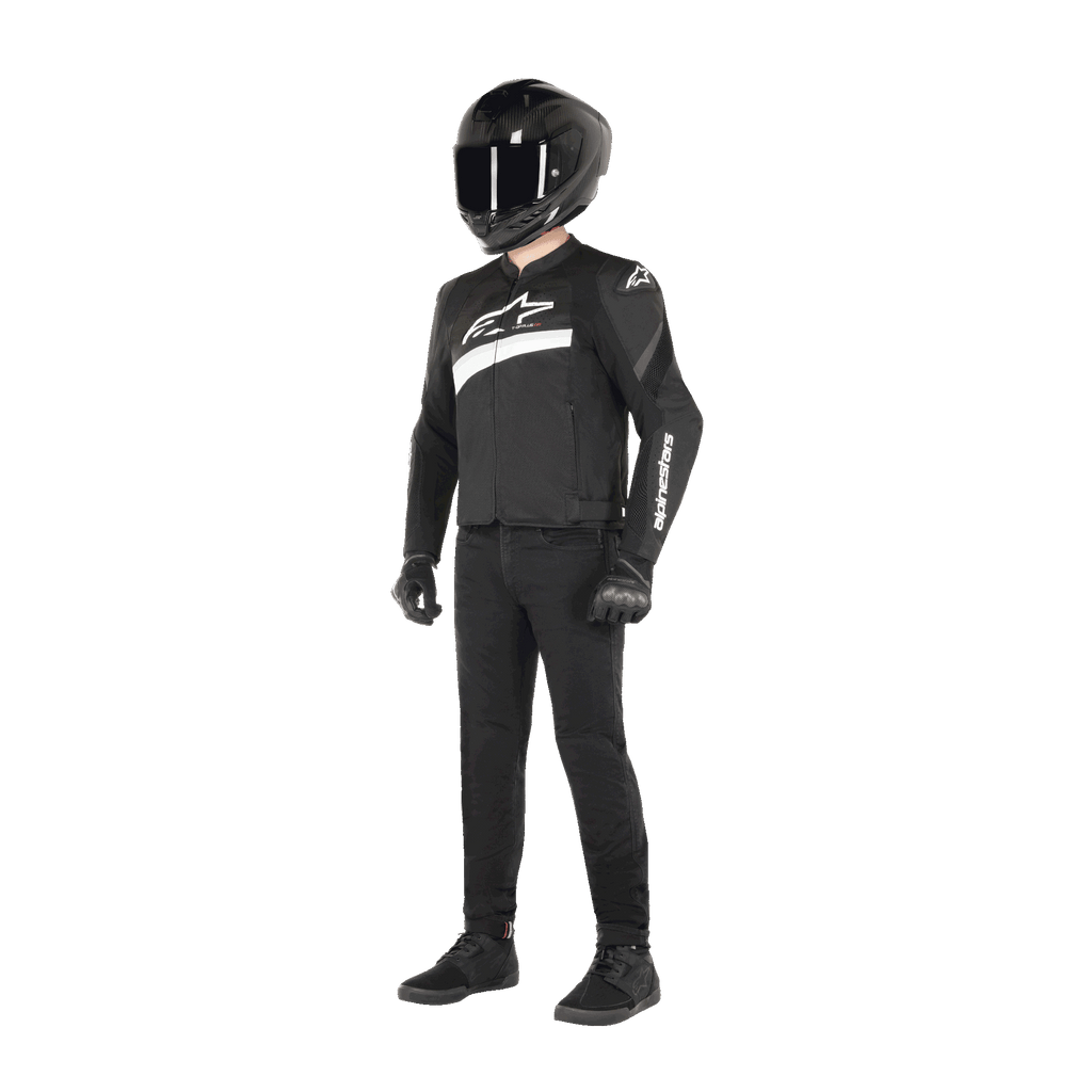 Fahrer in der Alpinestars T-GP Plus R V4 Airflow Jacke in Schwarz und Weiß, Textil-Motorradjacke mit Mesh-Einsätzen und weißem Alpinestars-Branding, kombiniert mit schwarzem Helm, schwarzen Handschuhen, schwarzer Hose und schwarzen Schuhen
