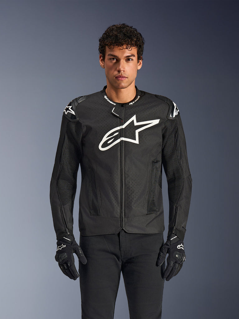 Alpinestars T-GP Air Jacket, Black motorcycle jacket with white logo, perforated ventilation panels, protective shoulder padding, worn with black and white gloves, sleek sporty design for street riding