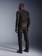 Männlicher Fahrer in der Rückansicht trägt die Alpinestars Viper Air V4 Jacke, Schwarz und Rot Fluo, mit einem orangefarbenen Astars-Logo auf dem unteren Rücken und den Schultern, Mesh-Textilkonstruktion, kombiniert mit passender schwarzer Motorradhose und Stiefeln.