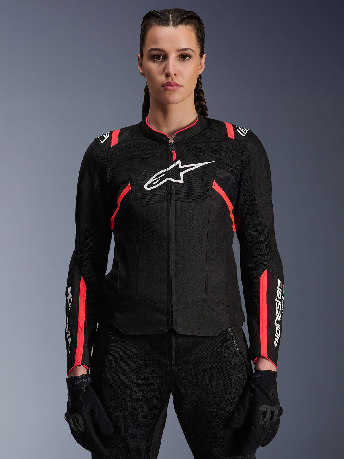 Alpinestars Stella T-Sps Air V2 Damenjacke, Schwarz und Diva Pink, Textil-Motorradjacke mit atmungsaktiven Mesh-Einsätzen und pinkfarbenen Akzenten, weißes Alpinestars-Logo auf der Brust, getragen von einem weiblichen Model mit schwarzer Fahrhose und Handschuhen.