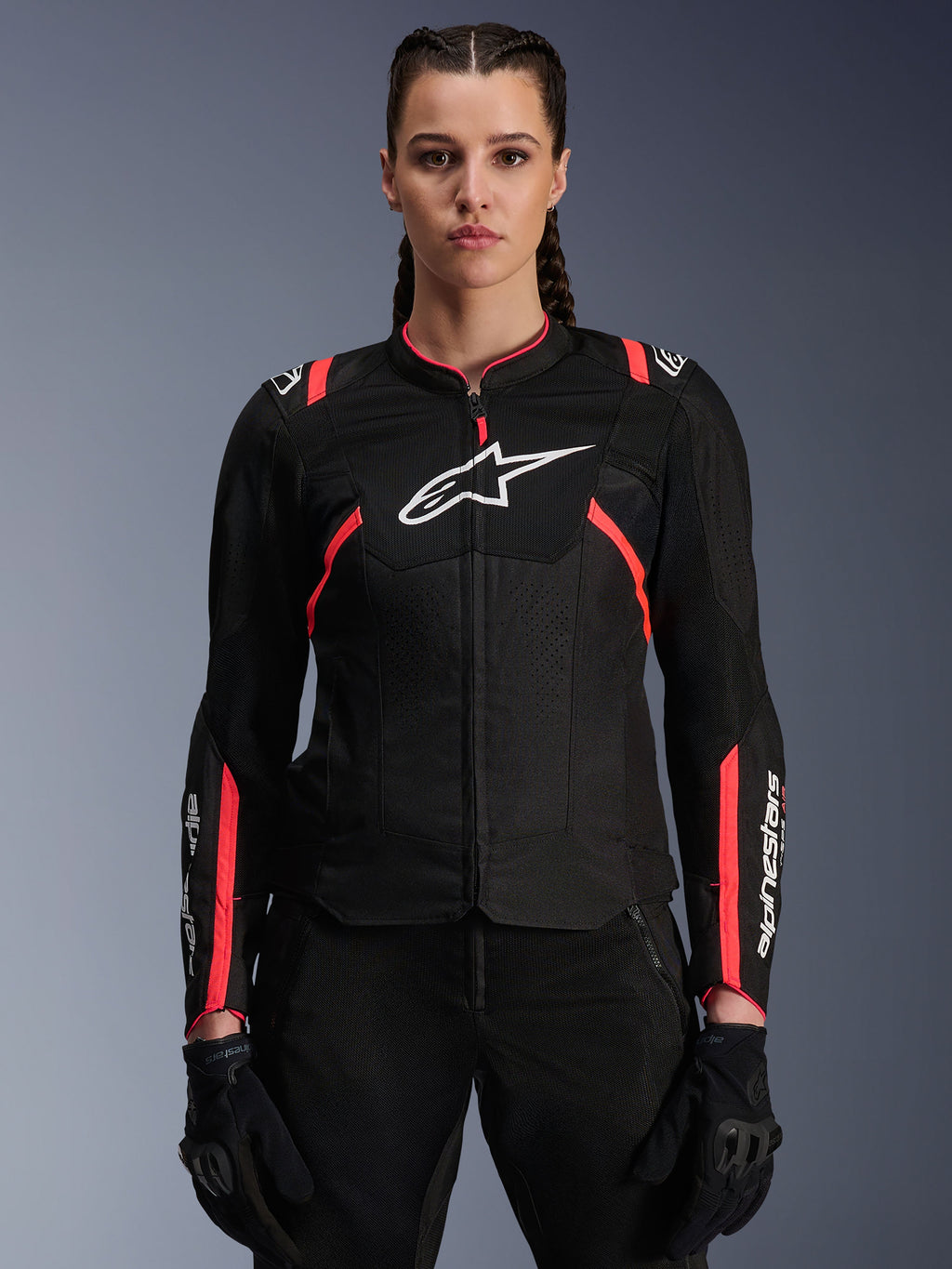 Alpinestars Stella T-Sps Air V2 Damenjacke, Schwarz und Diva Pink, Textil-Motorradjacke mit atmungsaktiven Mesh-Einsätzen und pinkfarbenen Akzenten, weißes Alpinestars-Logo auf der Brust, getragen von einem weiblichen Model mit schwarzer Fahrhose und Handschuhen.