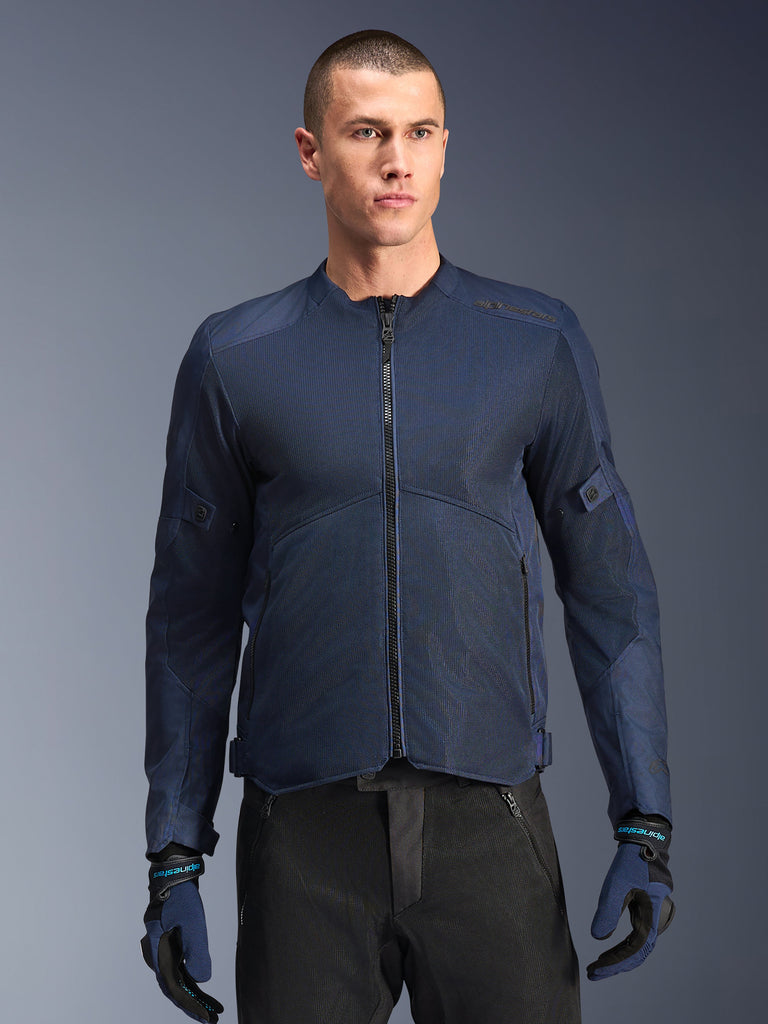 Alpinestars C-1 Air Jacke, blaue Motorradjacke, getragen von einem männlichen Model mit schwarzer Hose und passenden blau-schwarzen Handschuhen, Tech-Mesh-Einsätze für optimalen Luftstrom, cleanes urbanes Design mit Frontreißverschluss und dezentem Branding