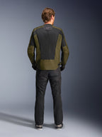 Rückansicht eines Fahrers in der Alpinestars C-1 Air Jacke in Khaki und Schwarz, mit einem großen Tech-Mesh-Rückenpanel zur Belüftung, kombiniert mit einer schwarzen Motorradhose, moderne urbane Straßenbekleidung.