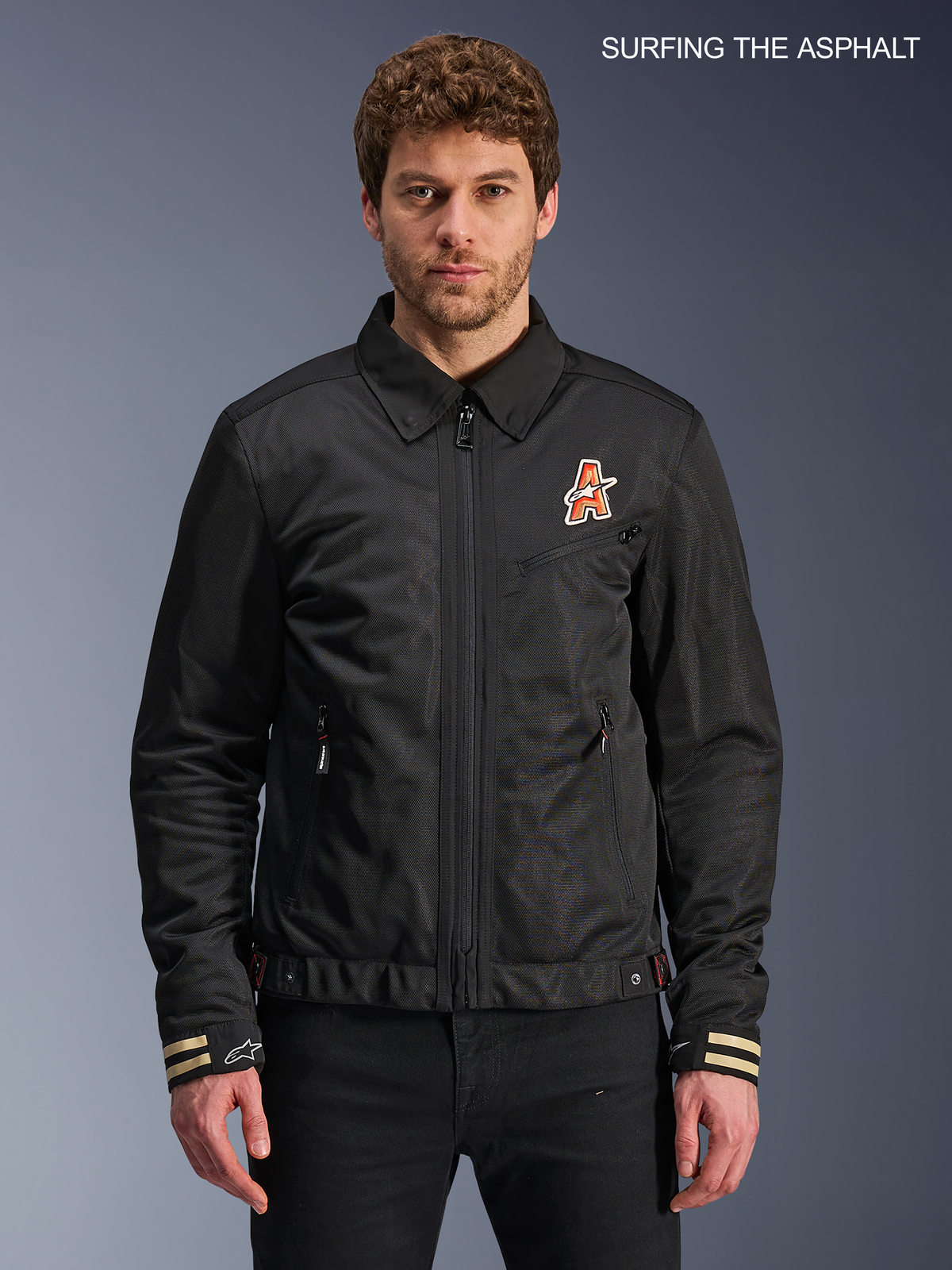 Alpinestars Ignite Air Jacke, urbane Herren-Motorradjacke in Schwarz, Vorderansicht am Model mit traditionellem Hemdkragen, club-inspirierten Brustgrafiken und CE-zertifizierter Konstruktion