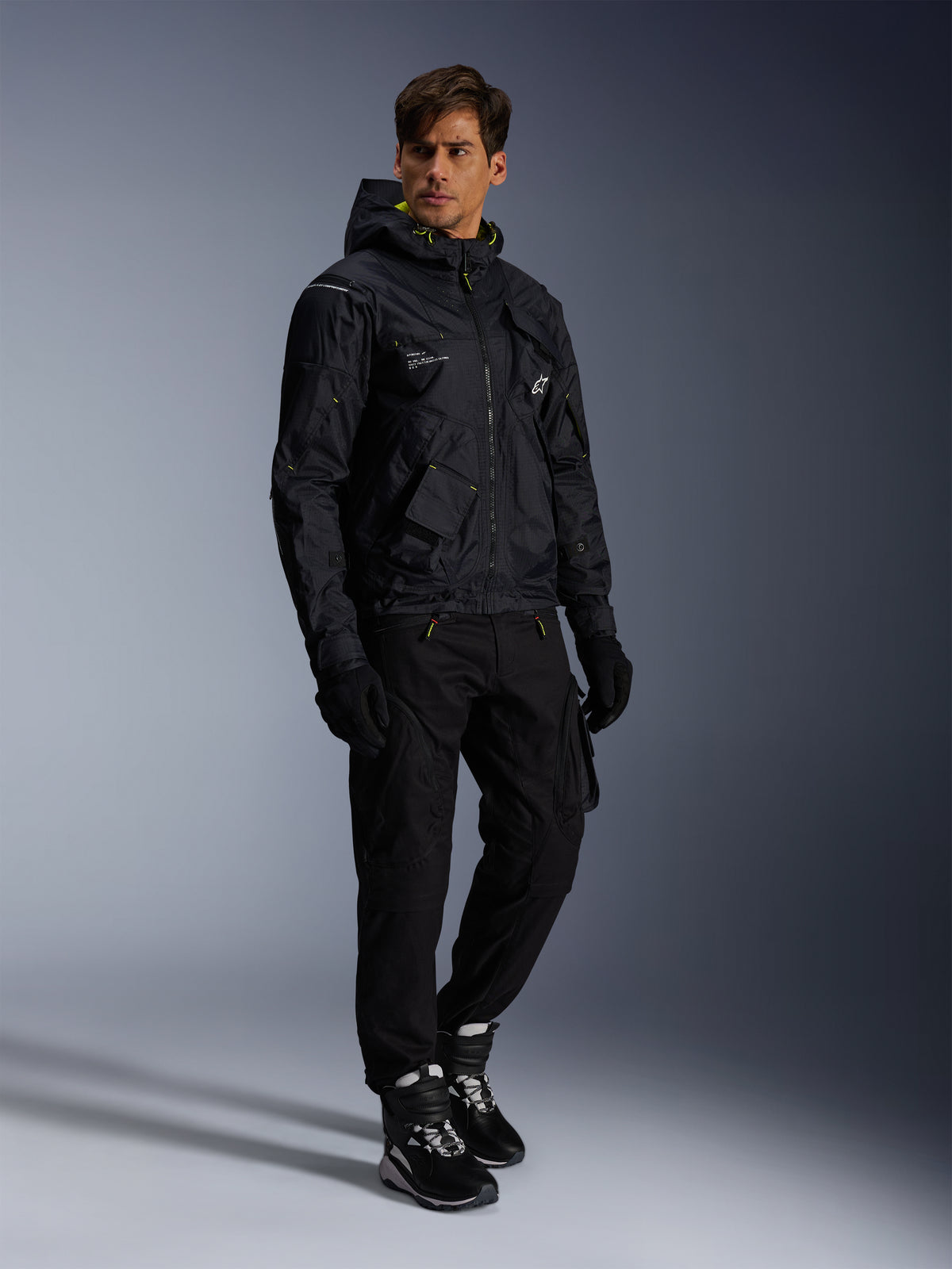 Alpinestars Mogress Air Jacke, Urbane Motorradjacke, Schwarz mit Lime Punch und weißen Akzenten, getragen mit schwarzer Motorradhose, Handschuhen und schwarz-weißen Stiefeln, zeitgenössisches, Utility-inspiriertes Design.