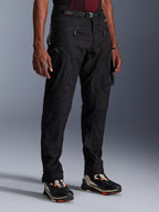 Alpinestars Acteon Hose, schwarze Motorradhose, an einem Model präsentiert, mit moderner, schmal zulaufender Silhouette, Cargo-Taschen mit Reißverschluss, verstellbarem Taillengürtel und technischen Sneakers, urbane Motorradbekleidung