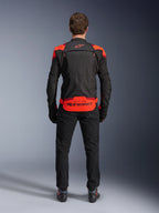 Alpinestars T-Stunt Air Jacke, Schwarz mit Red Fluo und dunkelroten Akzenten, Rückansicht am Model, kombiniert mit schwarzer Motorradhose und Stiefeln, markantes Alpinestars-Branding am unteren Rücken, modulares Design mit Mesh-Konstruktion für Belüftung