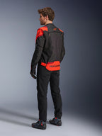 Mann in Alpinestars T-Stunt Air Jacke, Rückansicht, Schwarz, Fluo-Rot und Dunkelrot, Textil-Motorradjacke mit Mesh-Einsätzen und sportlichem Design, markantes Alpinestars-Branding auf dem unteren Rücken, kombiniert mit schwarzer Hose und Motorradstiefeln