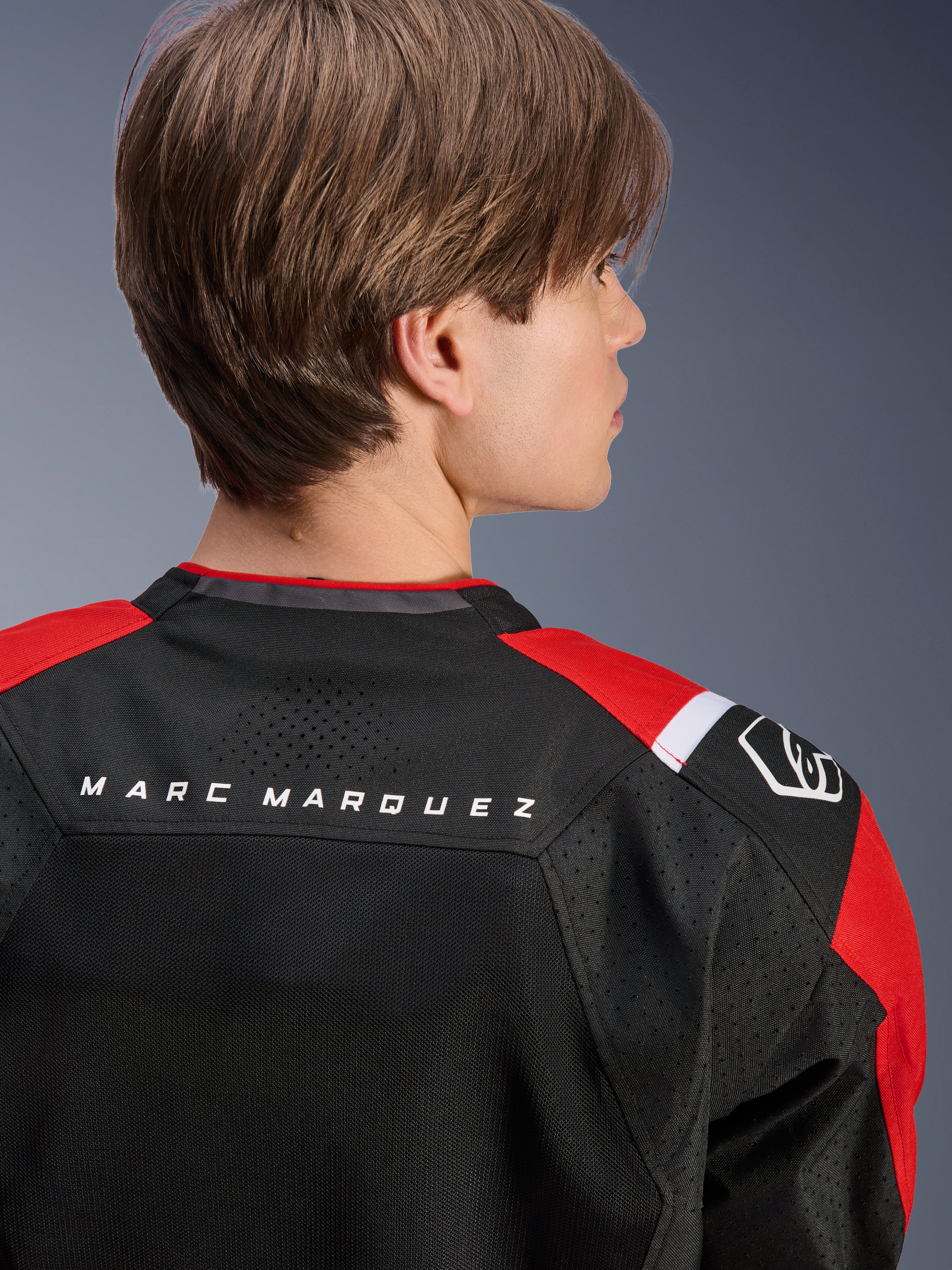 Alpinestars MM93 T-SPS Air V2 Jacket, rear view of the upper back and shoulders, Black with Bright Red and White details, 'MARC MARQUEZ' text across the yoke, featuring technical mesh panels and shoulder logo, urban sport motorcycle apparel