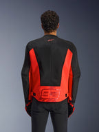 Rückansicht eines Mannes in der Alpinestars MM93 C-1 Air Jacke in Neonrot und Schwarz, mit einem großen „93“ Marc Marquez Logo auf dem unteren Rücken und leichten Mesh-Einsätzen zur Belüftung, kombiniert mit schwarzer Hose und Handschuhen.