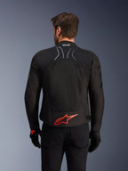 Alpinestars SMX Air Jacke, Rückansicht, Schwarz mit leuchtend rotem Alpinestars-Logo am unteren Rücken, mit High-Airflow-Tech-Mesh-Einsatz und Tech-Air-Ready-Branding, getragen von einem männlichen Fahrer mit schwarzer Hose und Handschuhen
