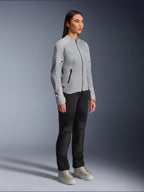 Frau in der Alpinestars Stella C-1 Air Jacke in Silber, leichte Textil- und Mesh-Motorradjacke, kombiniert mit einer schwarzen Fahrhose und lässigen Sneakern, schlichte urbane Riding-Ästhetik.