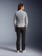 Frau in der Alpinestars Stella C-1 Air Jacke in Silber, Rückansicht, große Tech-Mesh-Einsätze zur Belüftung, reflektierendes Stern-Logo, kombiniert mit einer schwarzen Motorradhose und weißen Sneakern, moderne urbane Motorradausrüstung