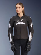 Alpinestars Stella T-GP Plus R V4 Jacke, Damen-Textilmotorradjacke, Schwarz-Weiß, getragen von einem weiblichen Model, mit weißen Streifenakzenten an Ärmeln und Brust, Alpinestars-Logo, sportliche Passform mit Frontreißverschluss