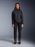 Alpinestars Actea Damenhose, schwarze Motorradhose für Damen mit roten Schriftelementen und Cargotaschen, getragen von einer Fahrerin mit schwarzer Kapuzenjacke, moderne urbane Motorradbekleidung