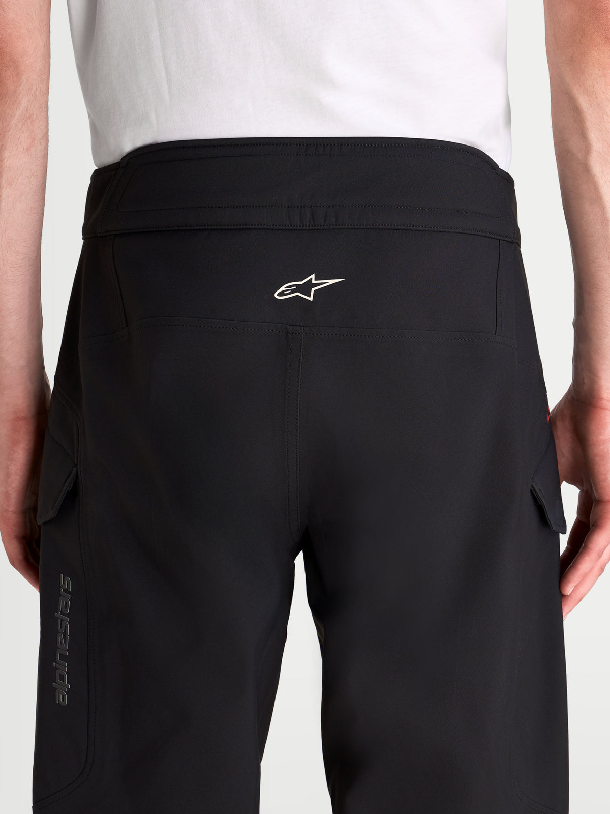 Alpinestars Juggernaut V 2 Drystar Hose, Herren-Motorradhose für die Stadt in Schwarz, Rückansicht des Modells mit hohem Bund, weißem Alpinestars-Logo und seitlichen Cargotaschen