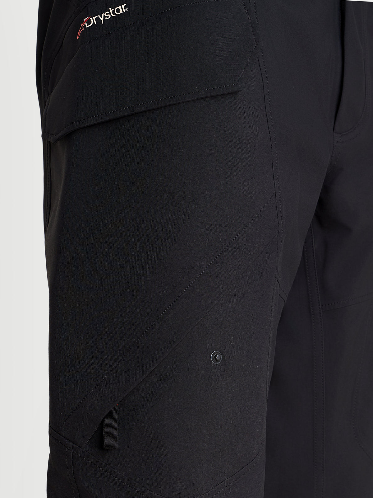 Alpinestars Juggernaut V 2 Drystar Hose, urbane wasserdichte Motorradhose in Schwarz, Nahaufnahme mit Hervorhebung der seitlichen Beintasche und dem Drystar-Branding