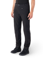 Alpinestars Alden Hose, Urbane Motorradhose, Schwarz, technisches Softshell-Gewebe mit normaler Passform, magnetische Gürtelschnalle, gesteppte Seiteneinsätze, Reißverschlusstaschen und dezentes Branding am Unterschenkel, getragen mit schwarzen Fahrerschuhen