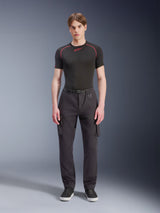 Alpinestars Flex-AST Cargo Hose, Schwarz, urbane Motorradhose, getragen von einem männlichen Model mit schwarzem kurzärmeligem Oberteil und Sneakern, Regular Tapered Passform, Cargotaschen und integrierte Gürtelschnalle