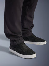 Alpinestars Flex-AST Cargo Hose, Schwarz, urbane Motorradhose, Nahaufnahme der schmal zulaufenden Beine und elastischen Säume, kombiniert mit schwarz-weißen Sneakern, technisches Polybaumwoll-Twill-Gewebe für entspannte Straßenfahrten.