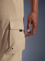 Alpinestars Flex-AST Cargo Pants, Light Beige, close-up of the side cargo pocket featuring an embroidered star logo on the flap, metal eyelet detail, and black herringbone tape accent, urban motorcycle riding pants.