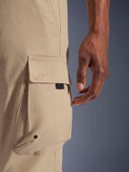 Alpinestars Flex-AST Cargo-Hose, urbane Motorradhose, Hellbeige, Detailaufnahme der seitlichen Cargotasche mit Ton-in-Ton gesticktem Logo, Metallöse und schwarzer Akzentlasche, strapazierfähiges Stretch-Textilgewebe