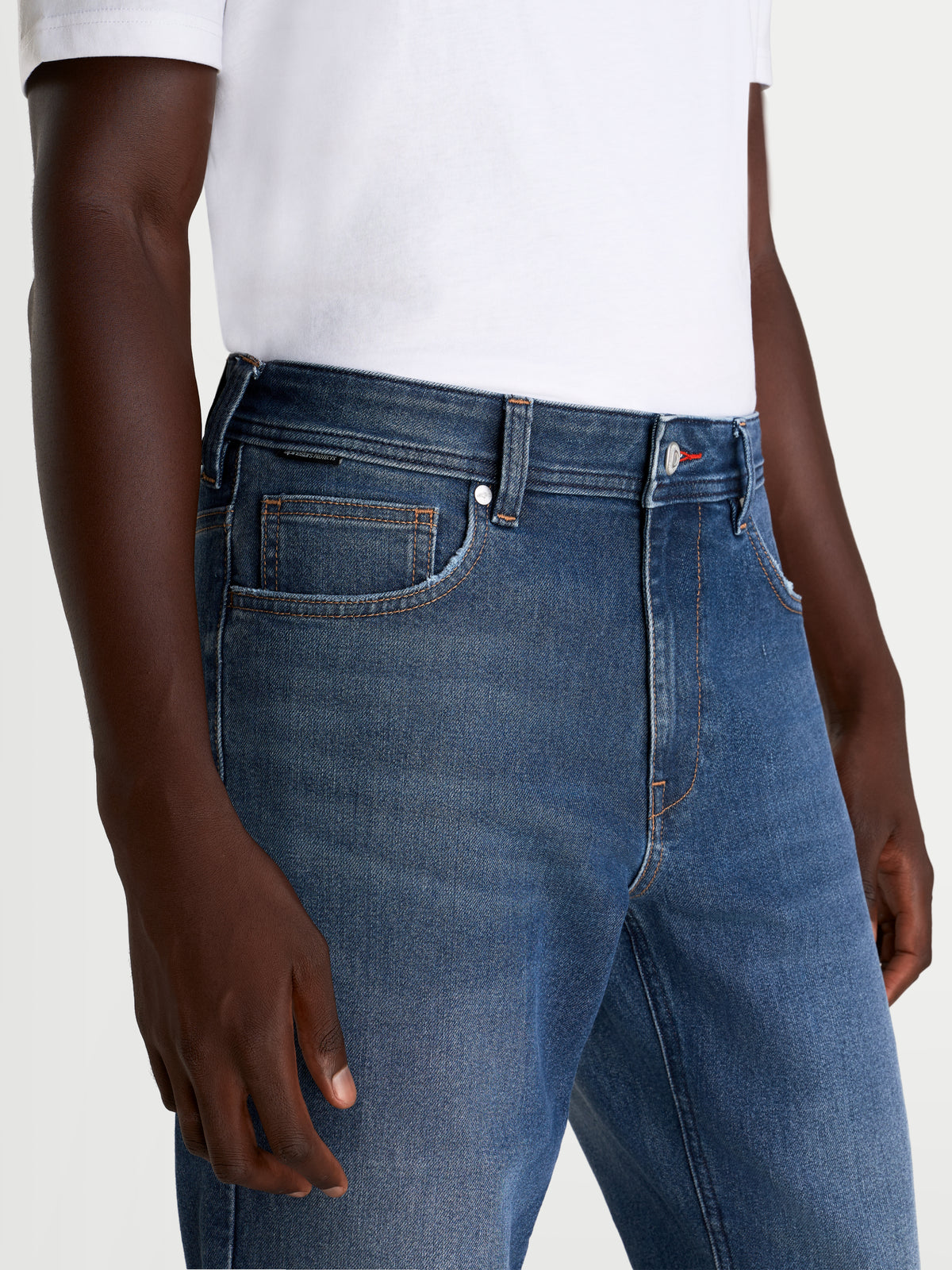 Alpinestars Flex Ast 8 Denim Hose, Herren-Urban-Motorradjeans in Mittelblau, Nahaufnahme der Taillen- und Fronttaschenkonstruktion, getragen von einem Model