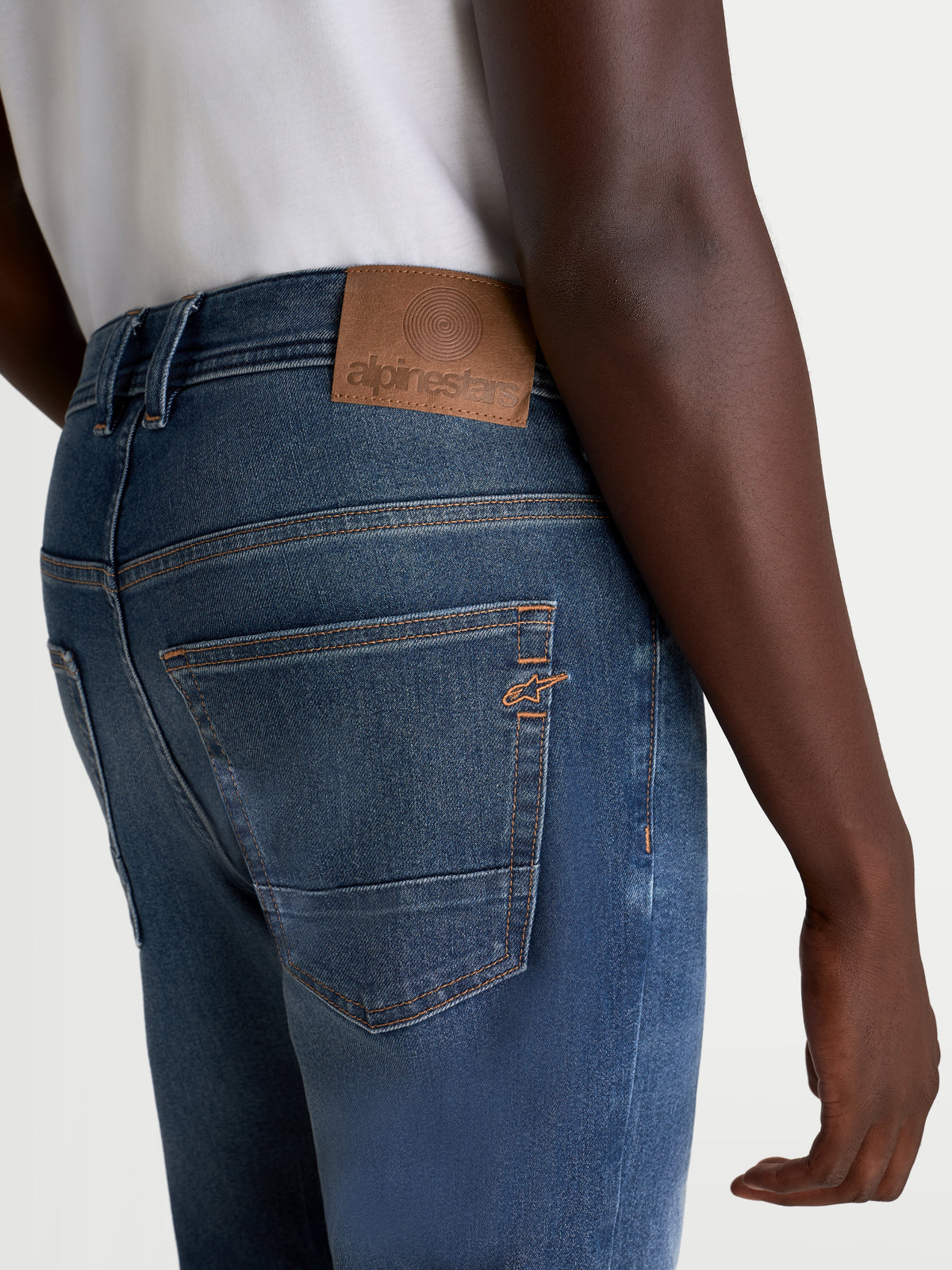 Alpinestars Flex Ast 8 Denim Hose, Herren-Urban-Motorradjeans in Mittelblau, Rückansicht mit Leder-Aufnäher, Kontrastnähten und gesticktem Astar-Logo auf der Tasche am Model