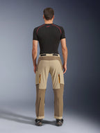 Alpinestars Maxdura Dual Hose in Walnut Aluminum, Rückansicht mit zweifarbigem Design in Braun und Tan, Adventure-Motorradhose mit Reißverschluss-Cargotaschen und verstärktem Gesäßbereich, getragen mit einem schwarzen Kompressionsshirt und Motorradstiefeln.
