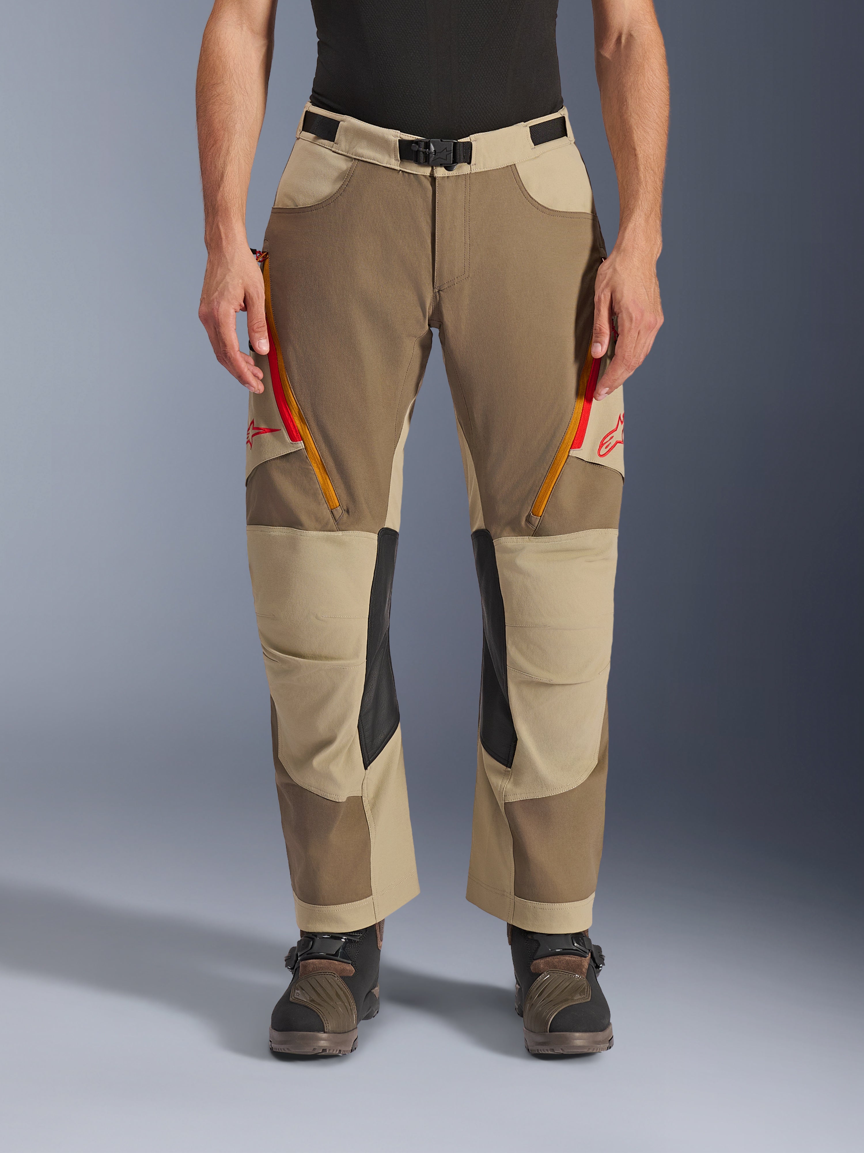 Alpinestars Maxdura Dual Hose, Walnut Aluminum, Adventure-Motorradhose mit rot und orangefarbenen Belüftungsreißverschlüssen an den Oberschenkeln, schwarzen Leder-Innenknie-Einsätzen, getragen mit einer schwarzen Basisschicht und robusten Stiefeln, strapazierfähiges, mehrtoniges Design für Dual-Sport-Fahrten