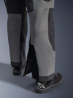 Alpinestars Maxdura Dual Hose, Adventure-Motorradhose, Dunkelgrau und Deep Gray, Nahaufnahme des verstellbaren Over-the-Boot-Beinsaums mit Druckknopfverschlüssen und verstärkten Einsätzen, getragen mit schwarzen Alpinestars Stiefeln, robustes technisches Design für Dual-Sport-Fahrten