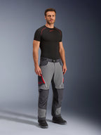 Alpinestars Maxdura Dual Hose, Adventure-Motorradhose, Dunkelgrau und Tiefgrau, getragen mit schwarzem Base Layer und Stiefeln, mit roten Belüftungsreißverschlüssen, verstärkten Einsätzen an Knien und Gesäß sowie einem Taillengürtel, sportliche Passform für den Dual-Sport-Einsatz