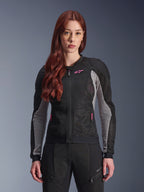 Alpinestars Stella Troop-Air Jacke für Damen, Motorrad-Meshjacke, Schwarz, Ash Gray und Pink Fluo, von einem Model mit passender Motorradhose getragen, mit belüfteter 2D-Tech-Mesh-Konstruktion und pinkfarbenem Logo-Detail, konzipiert für urbane Fahrten im Sommer.