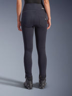 Alpinestars Stella Flex-AST Leggings, urbane Motorradhose, Schwarz, Rückansicht mit hoch geschnittener Skinny-Passform, zwei funktionelle Gesäßtaschen mit dezentem Branding, Stretch-Textilmaterial, kombiniert mit schwarzen Motorradschuhen.