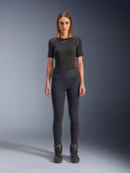 Alpinestars Stella Flex-AST Leggings, urbane Damen-Motorrad-Leggings in Schwarz, schmal geschnittenes High-Waist-Design, getragen mit einem schwarzen, kurzärmeligen Funktions-Oberteil und schwarzen Motorradstiefeln, mit Akkordeon-Kniepaneelen und einem modernen, minimalistischen Look.
