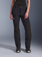 Alpinestars Stella Explore AST Hose, Damen-Motorrad-Abenteuerhose, Schwarz, mit Ripstop-Verstärkungen an den Knien, einer Cargo-Tasche mit Reißverschluss am Oberschenkel und dem 'Terra'-Logo, getragen mit schwarzen Stiefeln, schlankes Design für Adventure-Touren und Straßenfahrten.